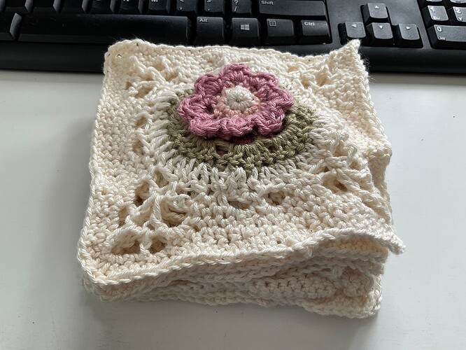 A stack of beige squares with a green circle and a pink flower on the top